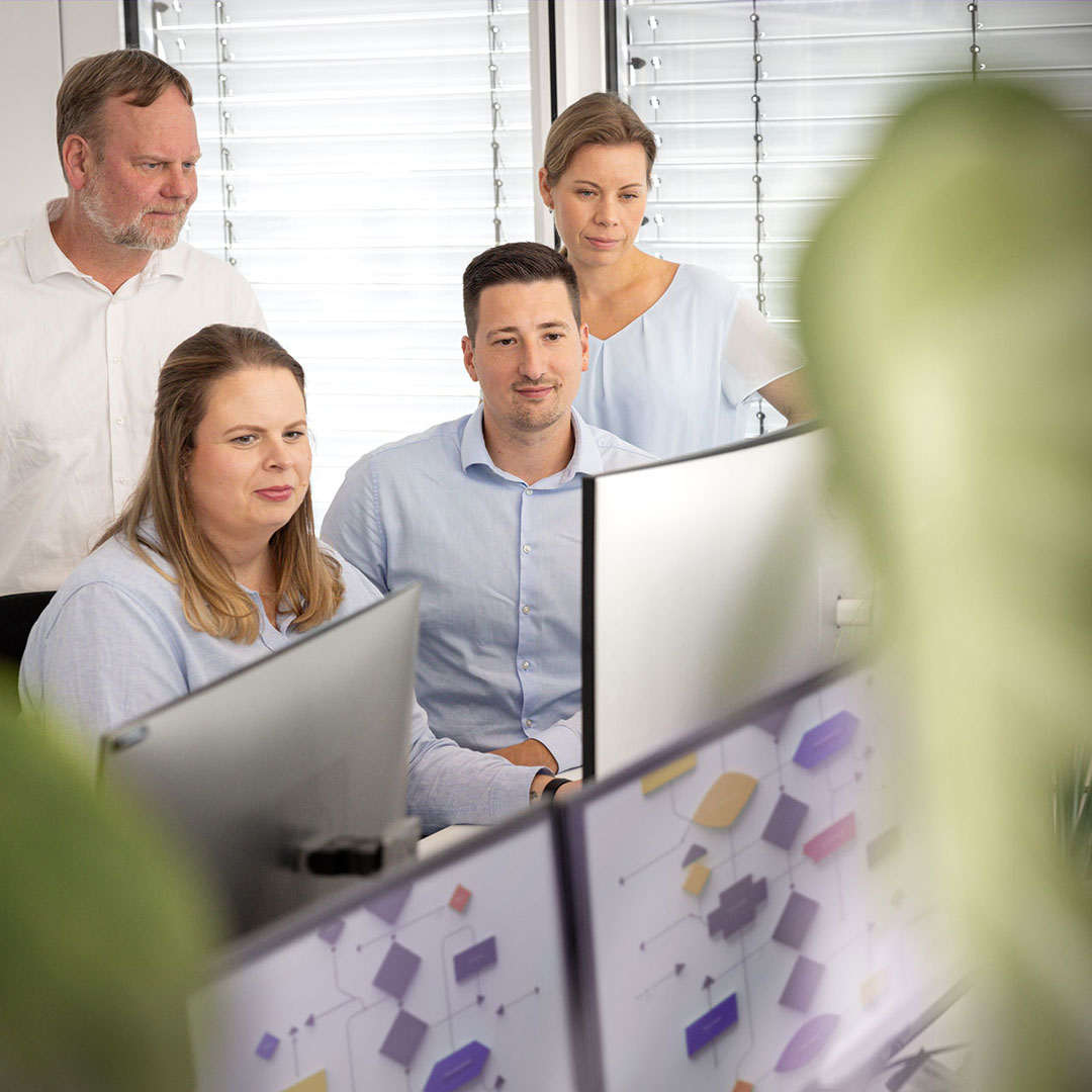 Ein Team der DOS analysiert einen Prozess des Fachbereichs Managementsysteme am Monitor